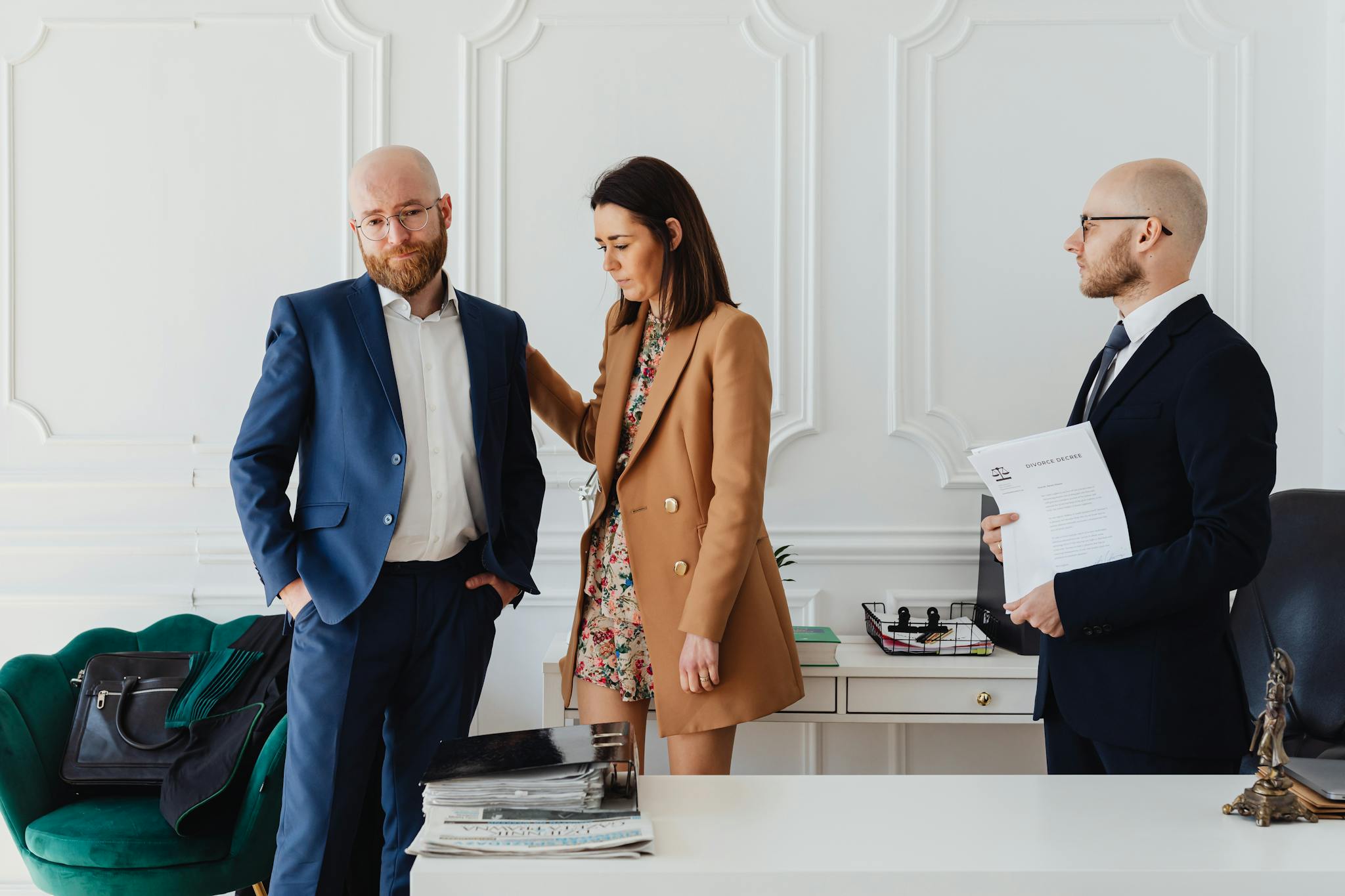 A couple with a lawyer in an office setting, reviewing divorce documents in formal attire.